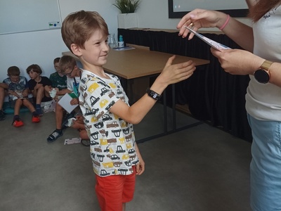 Dziecko odbiera certyfikat udziału w półkoloniach.