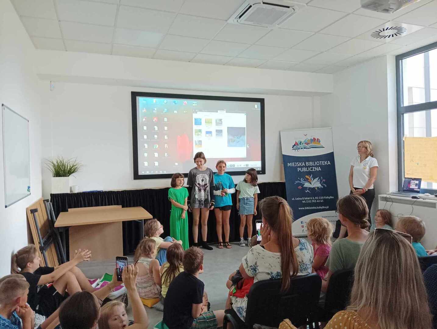 Dzieci prezentują swoje filmy przed publicznością.