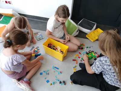 Dzieci budują z klocków LEGO skarbonkę.