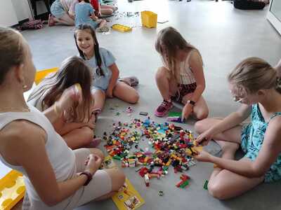 Dzieci budują z klocków LEGO skarbonkę.
