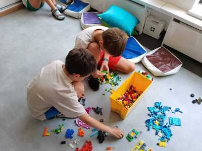 Dzieci budują z klocków LEGO skarbonkę.