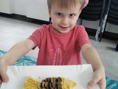 Chłopiec prezentuje rybkę z masy solnej jaką wykonał podczas zajęć.