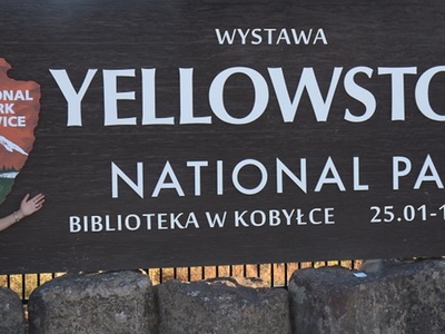 plakat informujący o wystawie z autorką fotografii na tle napisu Yellowstone National Park