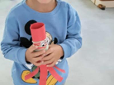 Dziecko trzyma ośmiornicę z papieru.
