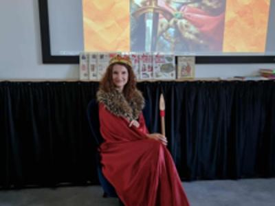 Kobieta siedzi na fotelu, trzyma berło.