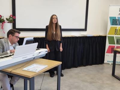 Mężczyzna gra na instrumencie. Dziewczyna śpiewa.