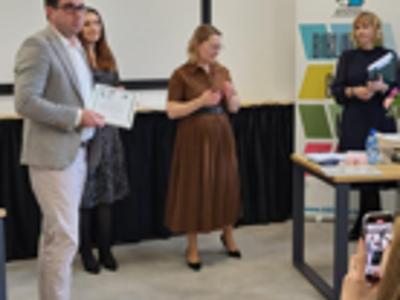 Prowadząca wręcza podziękowanie.