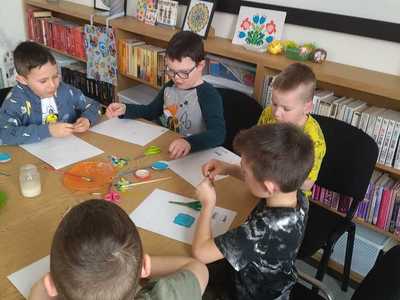 Dzieci ozdabiają szablon jajka wyciętymi z papieru elementami.