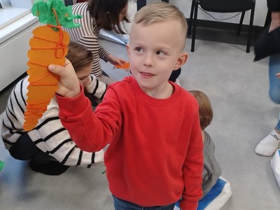 Chłopiec pokazuje swoją pracę plastyczną.