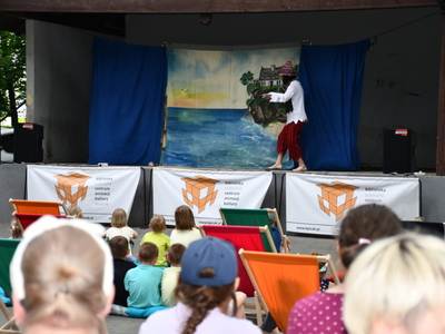 Na scenie aktorka z grupy teatralnej Krak-Art z Karowa wcielająca się w rolę Kostki, głównej bohaterki spektaklu, przed sceną dzieci na leżakach
