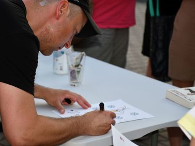 Czesław Mozil podpisujący ilustrację z bajki "Kraina Lodu"