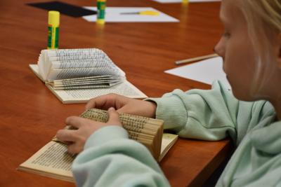 Warsztaty dla dzieci z rzeźbienia w książkach - uczestniczka podczas pracy