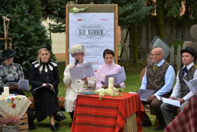 Lektorzy akcji Narodowego Czytania na tle scenografii w ogrodzie przy szkole w Liśniku Dużym