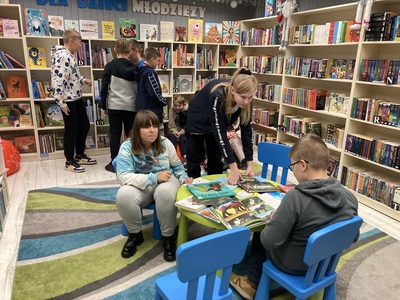 Dzieci przeglądają księgozbiór w bibliotece