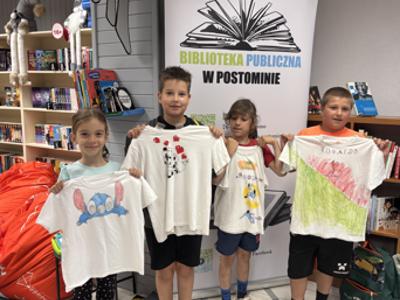 uczestnicy zajęć w bibliotece malują koszulki i torby