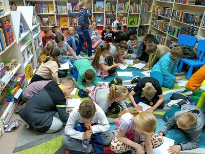 Dzieci  siedzące na dywanie w czytelni