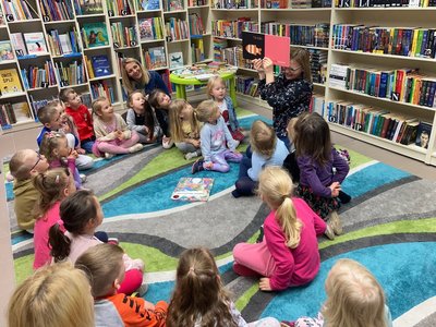 Dzieci siedzące na dywanie w bibliotece
