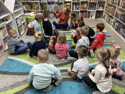 Dzieci siedzące na dywanie słuchają książki