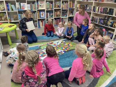dzieci słuchają książki czytanej przez bibliotekarza