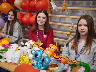 Wolontariuszki siedzące przy stanowisku z balonikami 