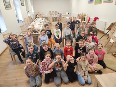 Dzieci siedzą na kocu i pozują do grupowego zdjęcia