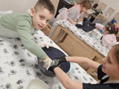 Dwóch chłopców ugniata ciasto na pizzę w misce 