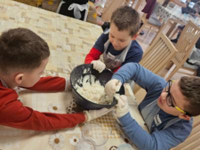 Trzech chłopców ugniata ciasto na pizzę w misce 