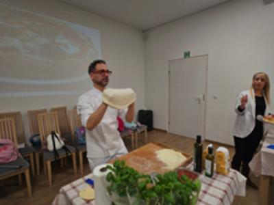 Kucharz z Włoch rozciąga ciasto na pizzę w rękach.