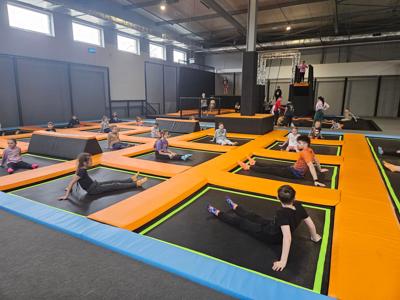 Dzieci siedzące na trampolinach jednoosobowych. Robią rozgrzewkę