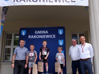 Zdjęcie grupowe chłopców na podium z Burmistrzem gm. Rakoniewice, Przewodniczącym oraz Zastępcą Przewodniczącego Rady Miejskiej.