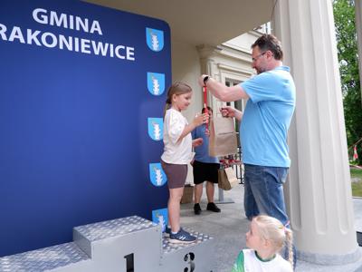 Arkadiusz Pawłowski - zastępca burmistrza gm. Rakoniewice wręcza medal stojącemu na podeście chłopcu za zajęcie 3 miejsca w biegach. 