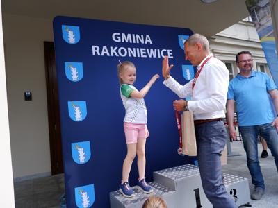 Krzysztof Krawczyk - przewodniczący Rady Miejskiej przybija &quot;piątkę&quot; stojącej na podeście dziewczynce za zajęcie 2 miejsca w biegach.