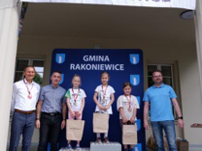 Zdjęcie grupowe dziewczyn na podium z Burmistrzem i Zastępcą Burmistrza gm. Rakoniewice oraz Przewodniczącym Rady Miejskiej.