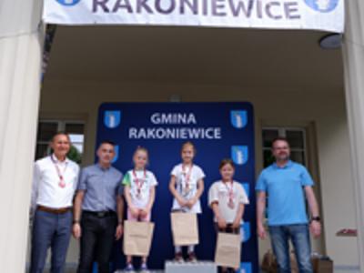 Zdjęcie grupowe dziewczyn na podium z Burmistrzem i Zastępcą Burmistrza gm. Rakoniewice oraz Przewodniczącym Rady Miejskiej.