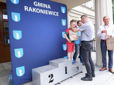 Dr Gerard Tomiak - burmistrz gm. Rakoniewice wręcza medal stojącemu na podeście chłopcu za zajęcie 3 miejsca w biegach. 