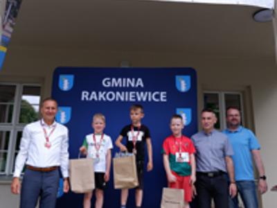 Zdjęcie grupowe chłopców na podium z Burmistrzem i Zastępcą Burmistrza gm. Rakoniewice oraz Przewodniczącym Rady Miejskiej.