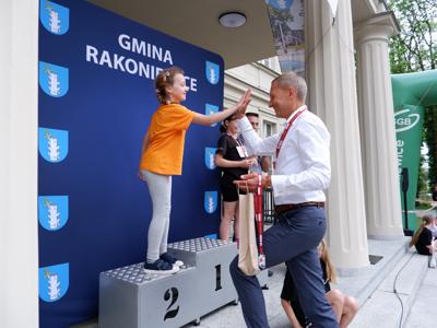 Krzysztof Krawczyk - przewodniczący Rady Miejskiej przybija &quot;piątkę&quot; stojącej na podeście dziewczynce za zajęcie 2 miejsca w biegach.