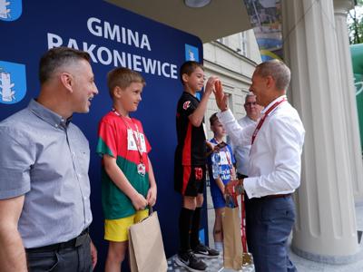 Krzysztof Krawczyk - przewodniczący Rady Miejskiej przybija &quot;piątkę&quot; stojącemu na podeście chłopcu za zajęcie 1 miejsca w biegach.