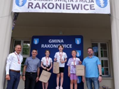 Zdjęcie grupowe dziewczyn na podium z Burmistrzem i Zastępcą Burmistrza gm. Rakoniewice oraz Przewodniczącym Rady Miejskiej.