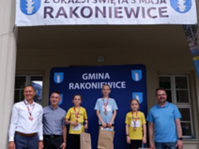 Zdjęcie grupowe dziewczyn na podium z Burmistrzem i Zastępcą Burmistrza gm. Rakoniewice oraz Przewodniczącym Rady Miejskiej.