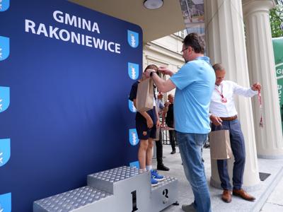 Arkadiusz Pawłowski - zastępca burmistrza gm. Rakoniewice wręcza medal stojącemu na podeście chłopcu za zajęcie 3 miejsca w biegach. 
