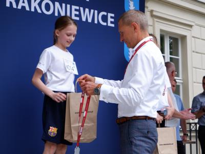 Krzysztof Krawczyk - przewodniczący Rady Miejskiej wręcza nagrodę stojącej na podeście dziewczynie za zajęcie 2 miejsca w biegach.