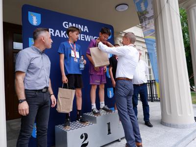 Krzysztof Krawczyk - przewodniczący Rady Miejskiej wręcza nagrodę stojącemu na podeście chłopcu za zajęcie 1 miejsca w biegach.