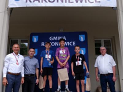 Zdjęcie grupowe chłopców na podium z Burmistrzem gm. Rakoniewice, Przewodniczącym oraz Zastępcą Przewodniczącego Rady Miejskiej.
