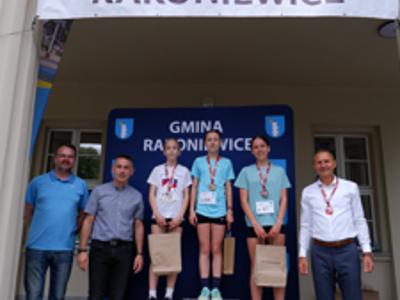 Zdjęcie grupowe dziewczyn na podium z Burmistrzem i Zastępcą Burmistrza gm. Rakoniewice oraz Przewodniczącym Rady Miejskiej.