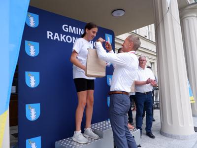 Krzysztof Krawczyk - przewodniczący Rady Miejskiej wręcza medal stojącej na podeście dziewczynie za zajęcie 2 miejsca w biegach.