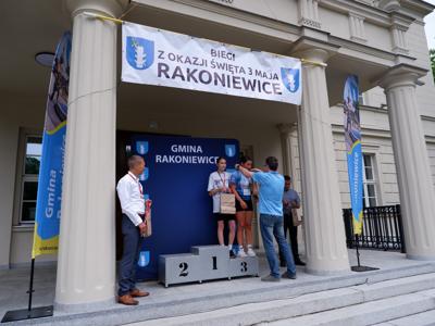 Arkadiusz Pawłowski - zastępca burmistrza gm. Rakoniewice wręcza medal stojącej na podeście dziewczynie za zajęcie 3 miejsca w biegach. 