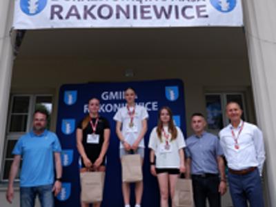 Zdjęcie grupowedziewczyn na podium z Burmistrzem i Zastępcą Burmistrza gm. Rakoniewice oraz Przewodniczącym Rady Miejskiej.