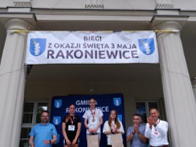 Zdjęcie grupowe dziewczyn na podium z Burmistrzem i Zastępcą Burmistrza gm. Rakoniewice oraz Przewodniczącym Rady Miejskiej.