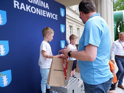 Arkadiusz Pawłowski - zastępca burmistrza gm. Rakoniewice wręcza medal stojącemu na podeście chłopcu za zajęcie 3 miejsca w biegach. 